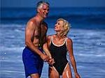 Imagem de um casal de meia-idade em trajes de banho que jogam na praia
