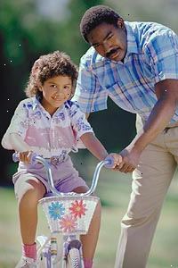 Imagem de um pai ensinando a filha a andar de bicicleta