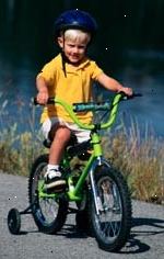 Imagem do menino novo, com um capacete, andar de bicicleta