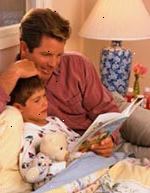 Imagem de pai ouvir o seu filho ler um livro na hora de dormir