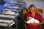Imagem de uma enfermeira segurando um bebê no berçário do hospital